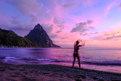 Man standing on beach against sky during sunset