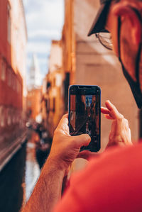 Midsection of man photographing with mobile phone