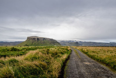 Road amidst field against sky