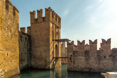 Old building by river against sky