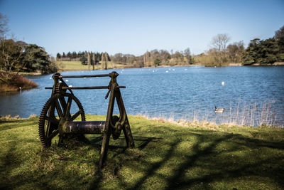 Machinery on grass against lake