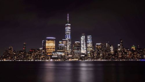 Illuminated buildings in city by river at night