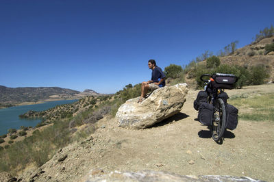 Man riding motorcycle on rock in mountains against clear sky