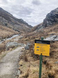 Information sign on road against sky