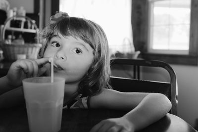 Girl looking away while having drink at table