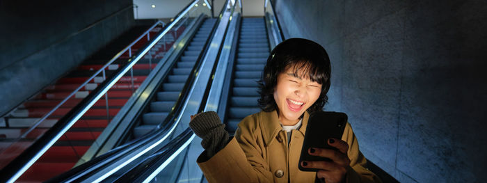 Portrait of young woman sitting on escalator