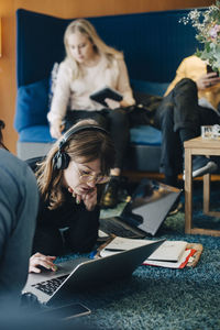 Young businesswoman using laptop while sitting amidst colleagues in cafeteria at office