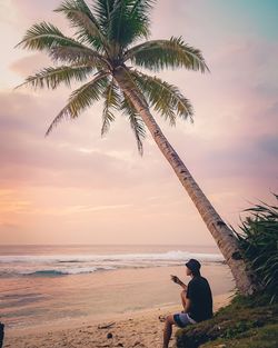 Man sitting on beach during sunset