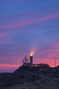 Lighthouse by sea against sky during sunset