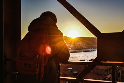 Rear view of man standing in city during sunset