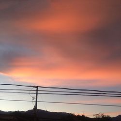 Electricity pylon against cloudy sky during sunset