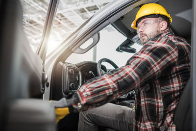 Side view of man working in car