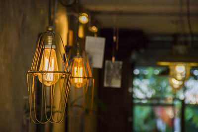 Close-up of illuminated light bulbs hanging at home