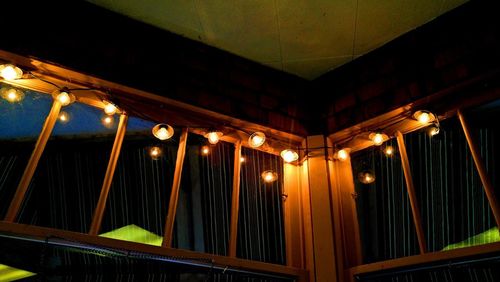 Low angle view of illuminated light bulbs hanging from ceiling