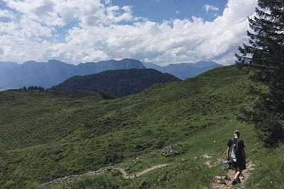 Rear view of man standing on mountain against sky