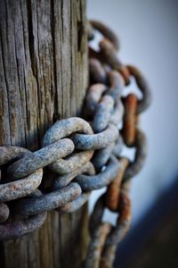 Close-up of rusty chain on wooden post