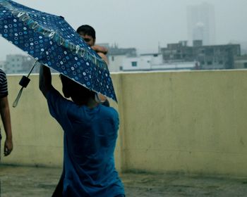 Midsection of man in city by sea against sky