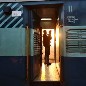 Silhouette father carrying son in train during sunset