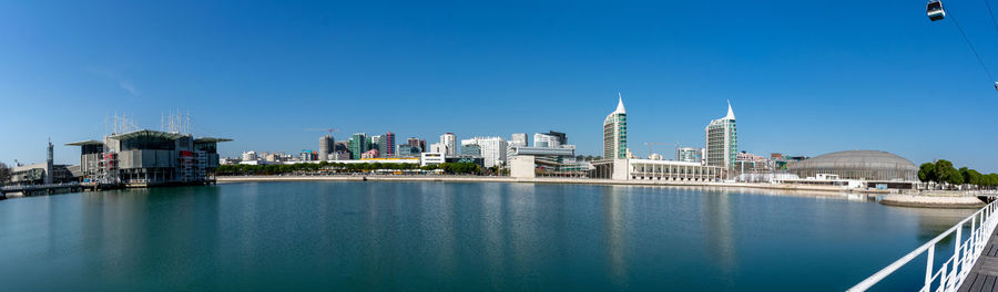 View of buildings by river against blue sky