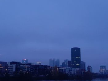 Illuminated buildings against blue sky at dusk