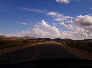 Road amidst landscape against sky seen through car windshield