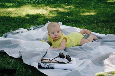 Portrait of cute baby boy lying on field