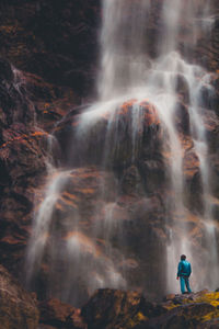 Full length of man standing against waterfall
