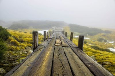 Walkway leading towards mountain against sky