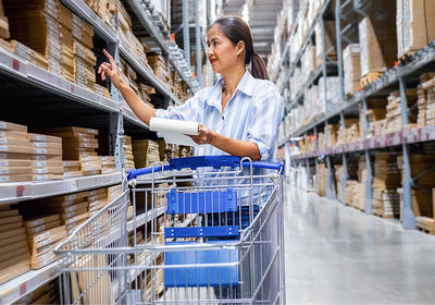 Woman checking list while standing in warehouse