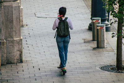 Full length rear view of woman walking on footpath