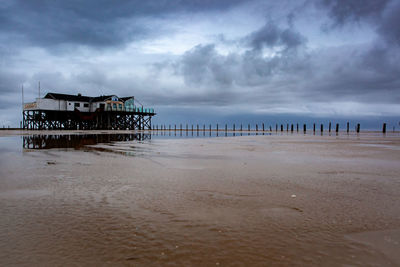 Wooden posts on beach by sea against sky