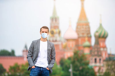 Portrait of young man standing against building