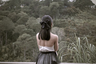 Rear view of woman standing against trees