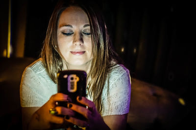 Smiling young woman using mobile phone at night
