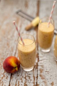 Close-up of peach and banana smoothie on wooden table