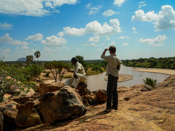 People standing on rock against sky