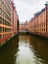 Canal amidst buildings in city against sky