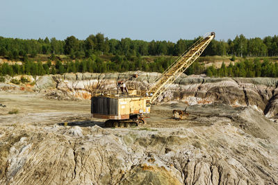 Abandoned machinery on rock by land against sky