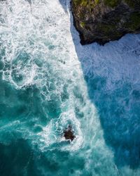 Shadows and waves crashing against the cliffs in bali, indonesia