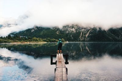 Man standing by lake against sky