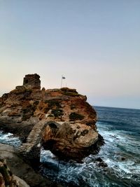 Rock formation on sea against clear sky