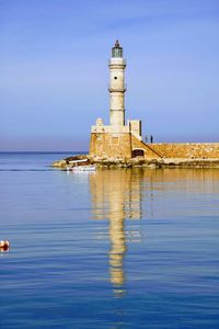 Lighthouse by sea against sky