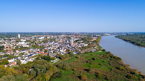 High angle view of river and cityscape against clear blue sky