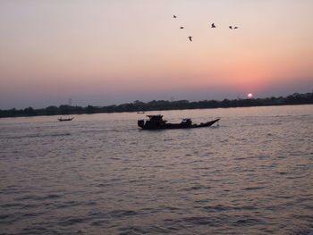 Silhouette boat in sea against sky during sunset