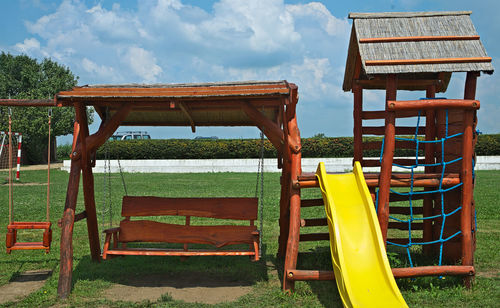 Empty chairs and table in park against sky