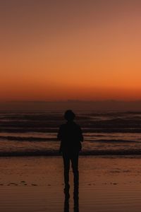 Silhouette man standing on beach during sunset