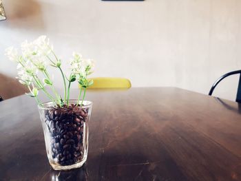 Close-up of flowers in glass with coffee beans on table