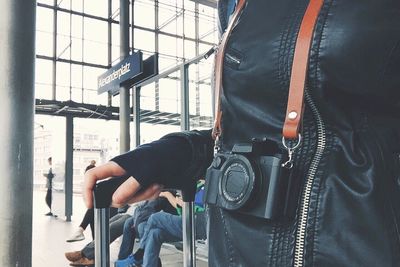 Midsection of woman with camera at airport