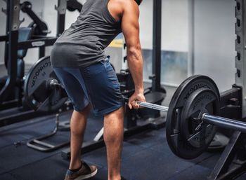 Low section of young man lifting dumbbell in gym