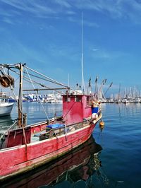 Fishing boats moored in harbor against sky